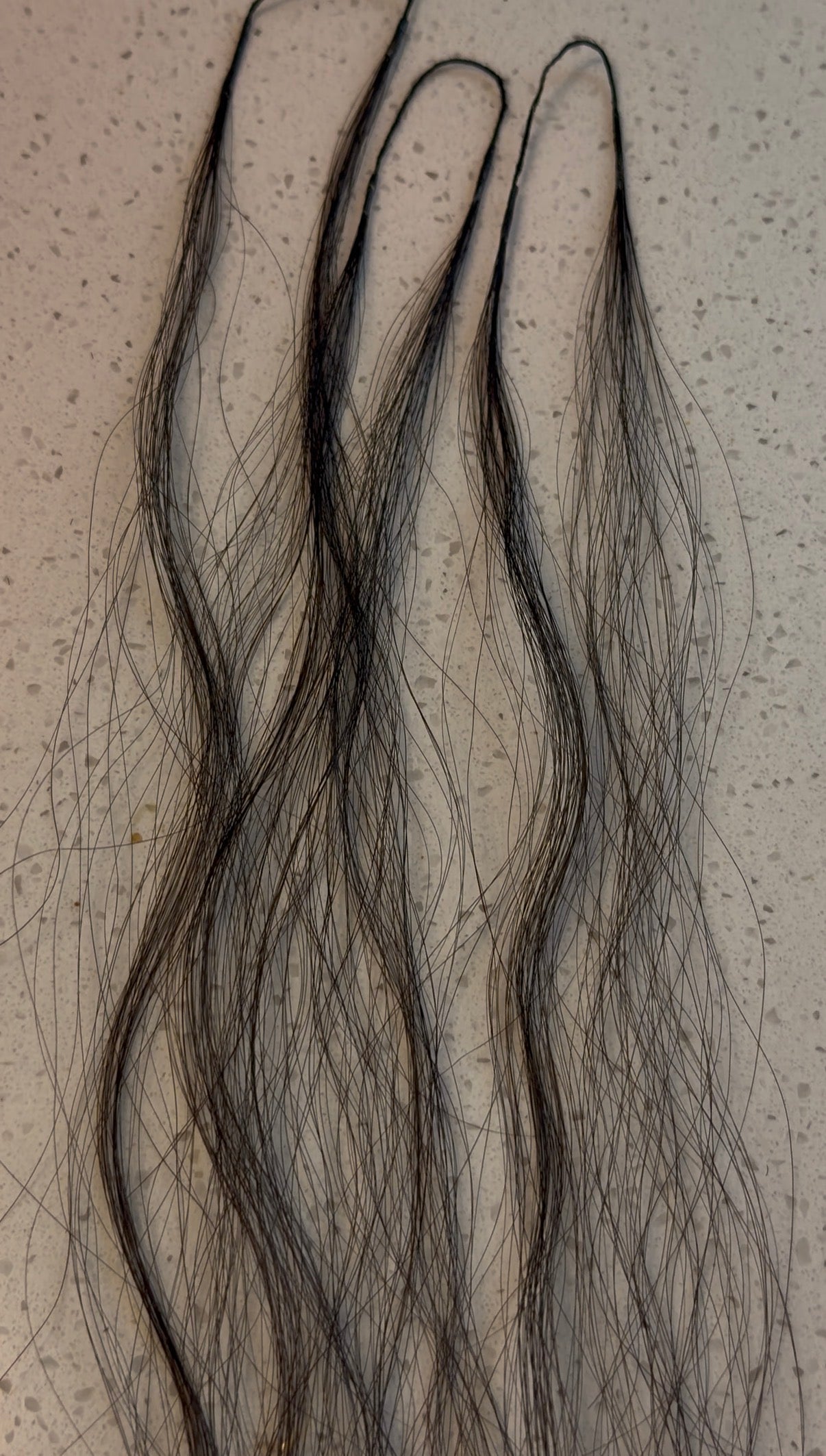 Three crochet hair strands on a textured beige background