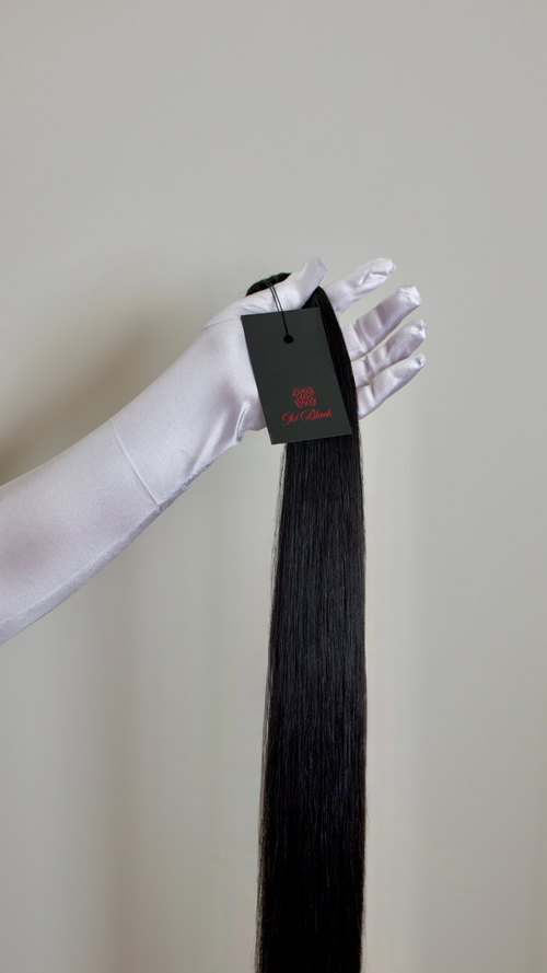 Black hair extension with a visible brand tag on a plain background
